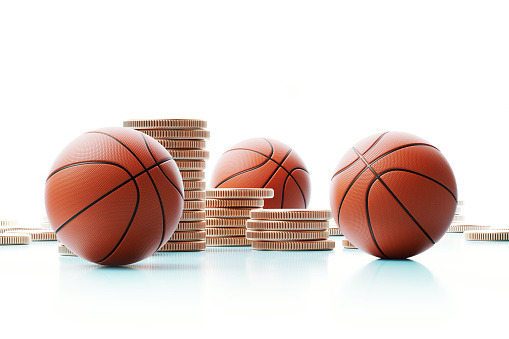 Basketball balls and coin stacks on white background.  Horizontal composition with copy space copy space. Gambling and sport betting concept.