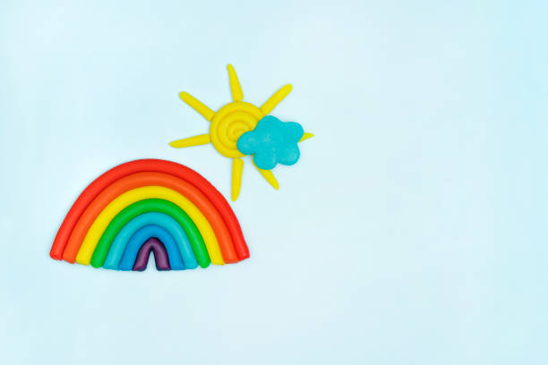 istock Plasticine colorful rainbow, blue cloud, yellow sun with rays on blue background. Plasticine creativity, children's hobby, toddler development concept 1455284974