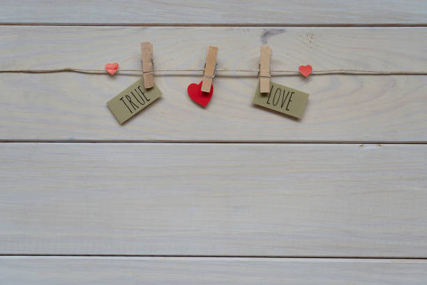 Red hearts on rope with clothespins, on a grey background