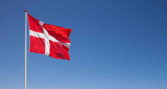 Danish national flag waving in the wind against blue sky