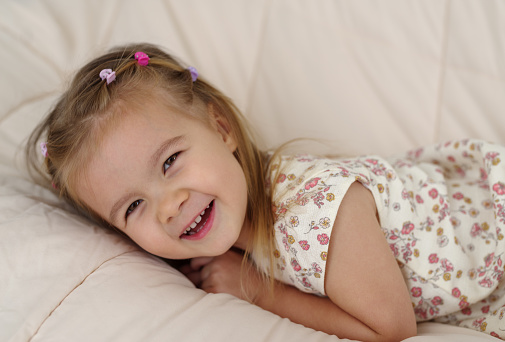 Lifestyle portrait of a female child as she lays on her bed