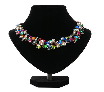 Stylish necklace with gemstones on jewelry bust against white background