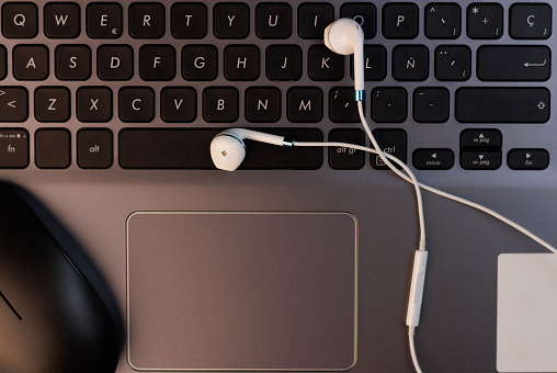 Detailed background of a laptop keyboard, mouse and small wired headphones