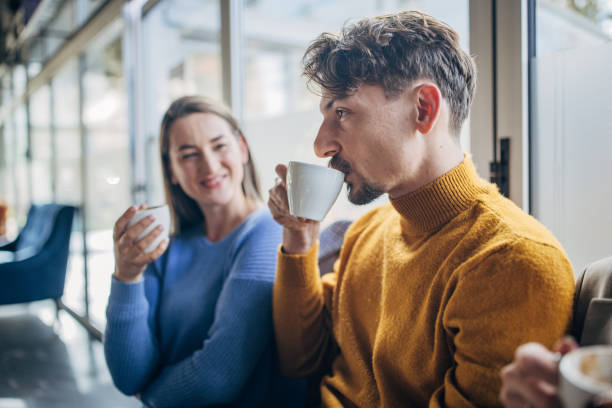 Smiling and happy heterosexual couple standing together with red coloured coffee mugs