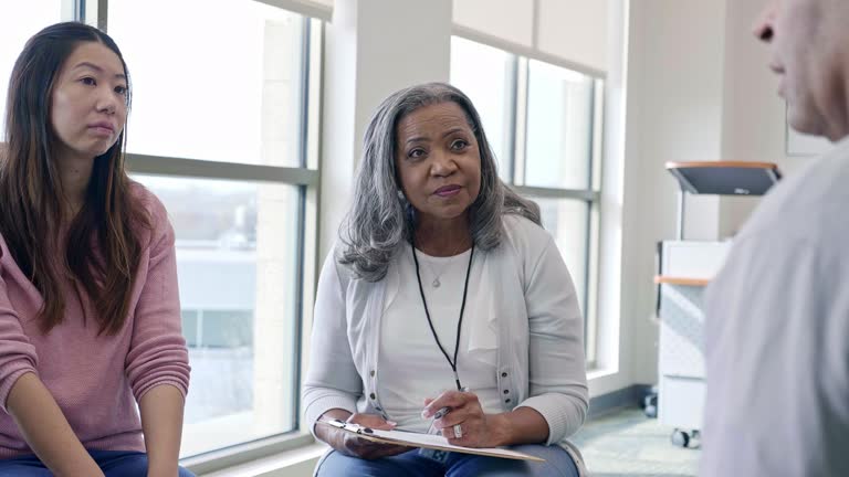 Caring female counselor listens to mature man during group therapy session