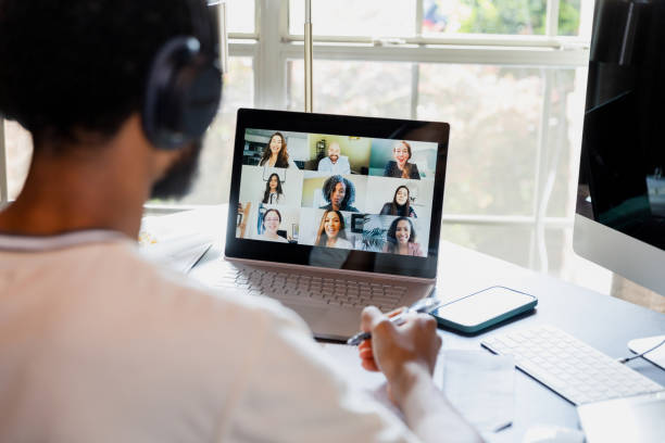 Over-the-shoulder view unrecognizable male college student attending online class stock photo