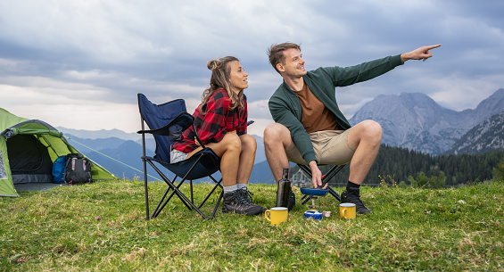 Outdoor camping adventure, preparing a meal in the mountains and enjoying a beautiful day in nature. Healthy lifestyle and simple living concept.