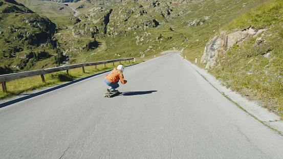 Cinematic downhill longboard session. Young woman skateboarding and making tricks between the curves on a mountain pass. Concept about extreme sports and people