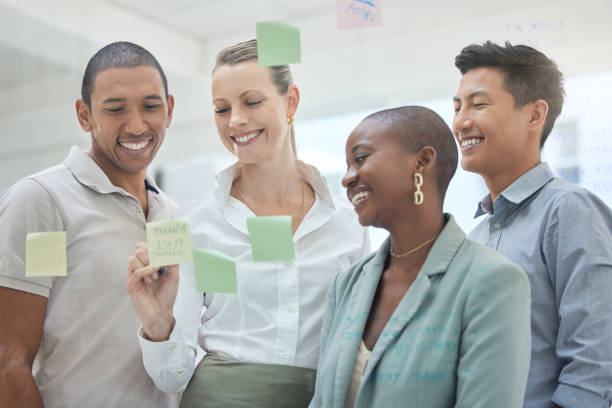 istock Teamwork, planning and strategy with sticky notes on glass in an office and a business team working together. Meeting, schedule and collaboration with a female leader and employee group in a workshop 1455295775