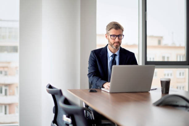 istock Confident businessman with laptop sitting at office desk and working 1455296422