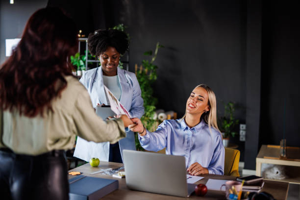 istock Businesswoman handing hew coworker a document while working at the office together 1455297526
