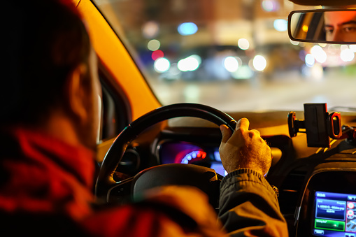 Man driving his car at night with unfocused lights from other vehicles and the city