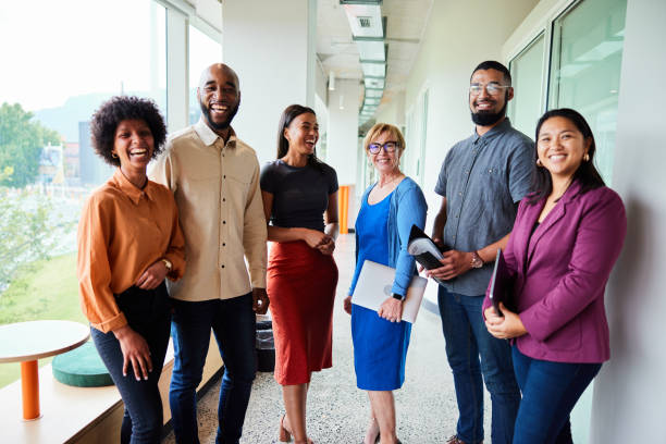 istock Laughing businesspeople standing together in an office hallway 1455298083