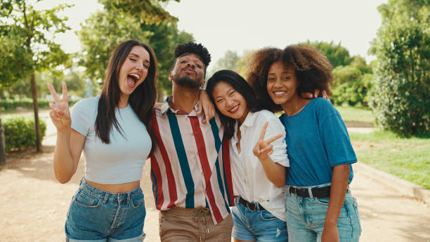 istock Happy, lovely multiethnic young people posing for the camera on summer day outdoors. group of friends hugging each other smiling at the camera while standing on path in the park 1455298549