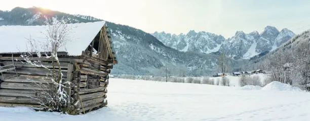 wooden cabin next to the Dachstein mountins in Gosau with sunlight .