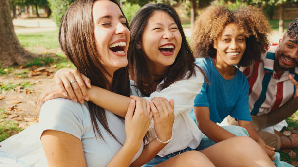 istock Happy multiethnic young people posing for the camera at picnic on summer day outdoors. Group of friends looking at the camera and laughing merrily 1455298784