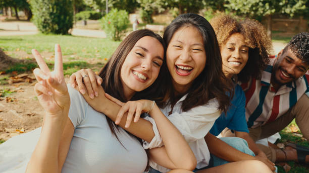 istock Happy multiethnic young people posing for the camera at picnic on summer day outdoors. Group of friends looking at the camera and laughing merrily 1455298789