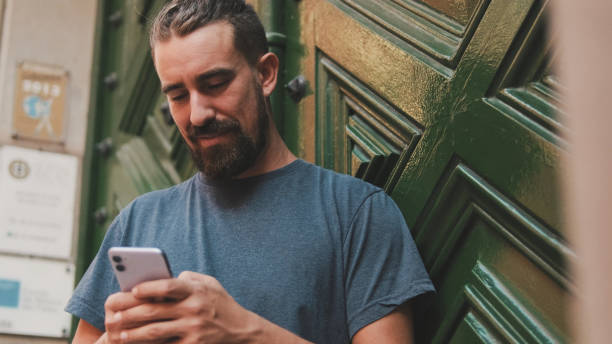 istock Young man with beard uses an application on smartphone 1455299672