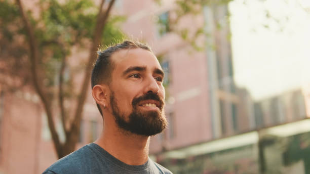 istock Young smiling man with beard walking and looking around at the old city background 1455299711