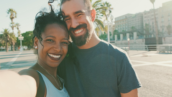 Close-up of interracial smiling couple in love taking selfie
