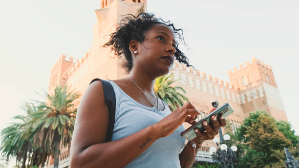 istock Young mixed race woman is using cell phone, looking at the application map on her smartphone 1455300111