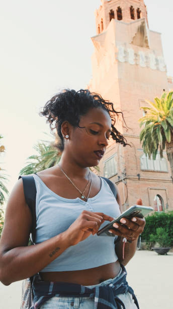 istock Young mixed race woman is using cell phone, looking at the application map on her smartphone 1455300140