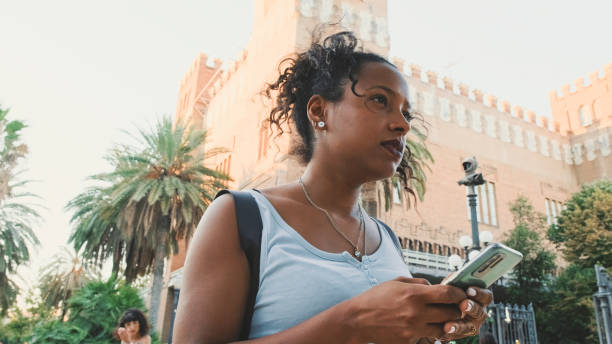 istock Young mixed race woman is using cell phone, looking at the application map on her smartphone 1455300159