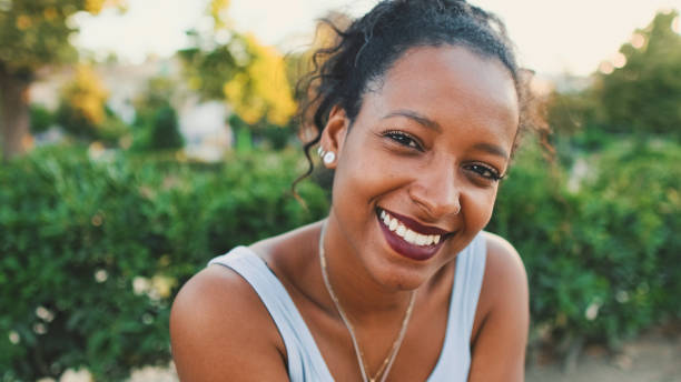 istock Young mixed race woman sitting on park bench, smiling, looking around 1455300904