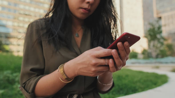 istock Close-up, Young girl uses smartphone while sitting on modern buildings background 1455301062