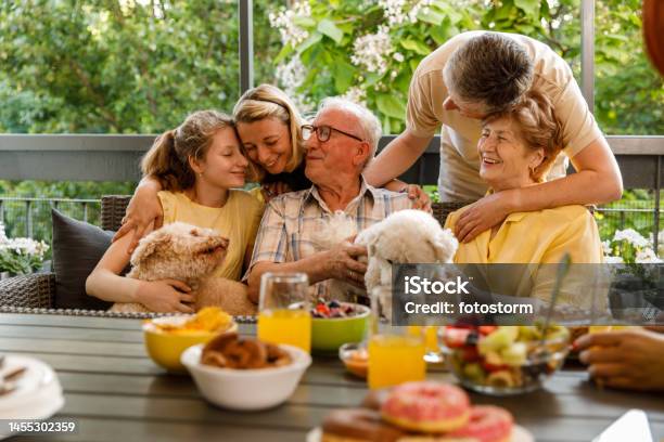 Three Generation Family Cuddling And Bonding During A Celebratory Party On The Balcony Stock Photo - Download Image Now