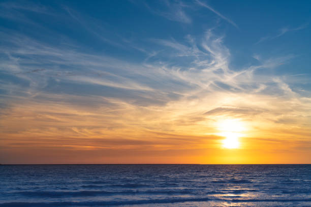 ciel de coucher de soleil sur l’horizon de la mer avec des couleurs bleues et orange dorées - ciel romantique photos et images de collection