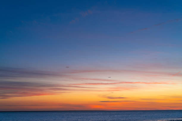 ciel de coucher de soleil sur l’horizon de la mer avec des couleurs bleues et orange dorées - ciel seulement photos et images de collection