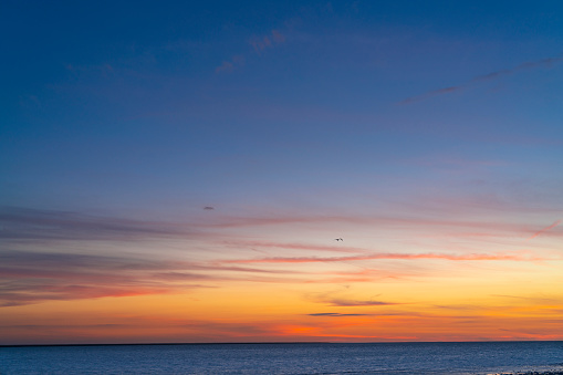 Sunset sky over the sea horizon with blue and golden orange colors at dusk background