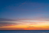 Sunset sky over the sea horizon with blue and golden orange colors