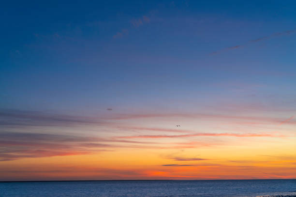 Sunset sky over the sea horizon with blue and golden orange colors Sunset sky over the sea horizon with blue and golden orange colors at dusk background sky only stock pictures, royalty-free photos & images
