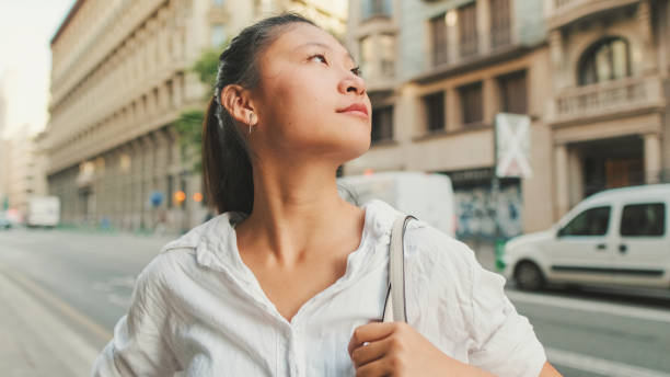 istock Young woman using mobile phone while standing next to the road. Girl looks around 1455302811