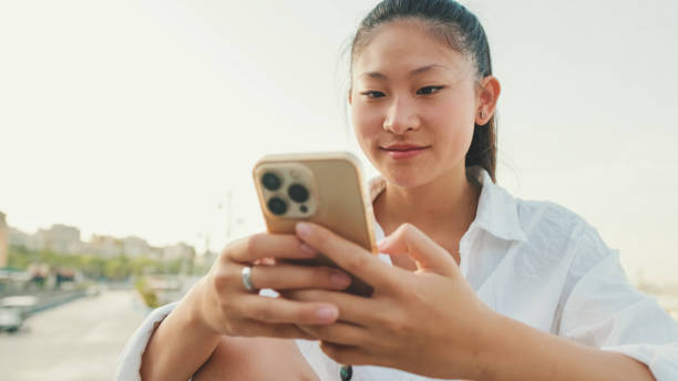 istock Closeup, Smiling young woman using mobile phone on seascape background 1455302841