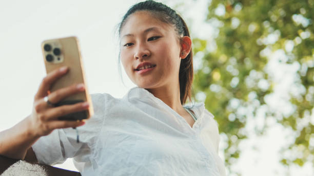 istock Young woman sitting on bench and using mobile phone 1455302917