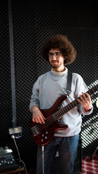 istock curly haired guitarist plays electric guitar in the studio 1455303045