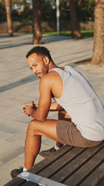 istock Young bearded male athlete is resting after training sitting on bench on modern background 1455304590