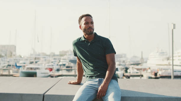 istock Young man enjoys relaxing while sitting in the harbor with yachts on the background 1455305235