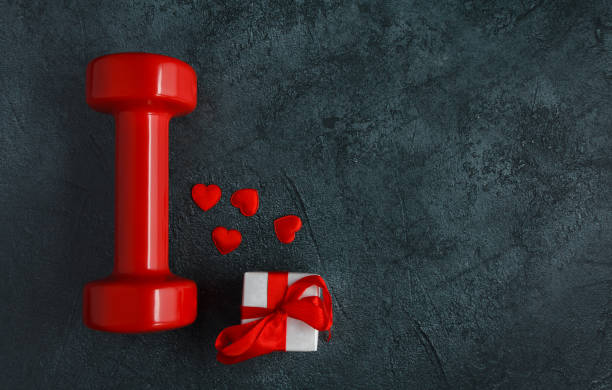 istock Red gym dumbbell and engagement ring gift box. Love composition for Valentine's Day, with copy space. 1455305257