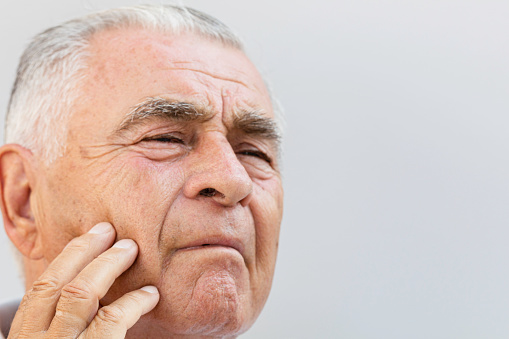 Unrecognizable caucasian senior man with toothache holding his chin.