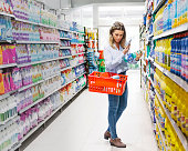 Woman with shopping basket buying groceries in supermarket