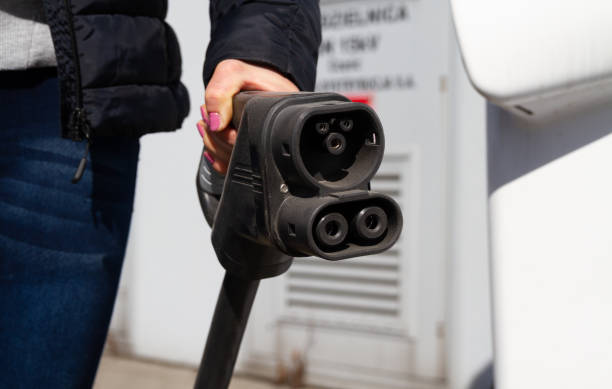 istock Woman holding fast charging socket type 2 for electric vehicles at EV car charging station. 1455306451