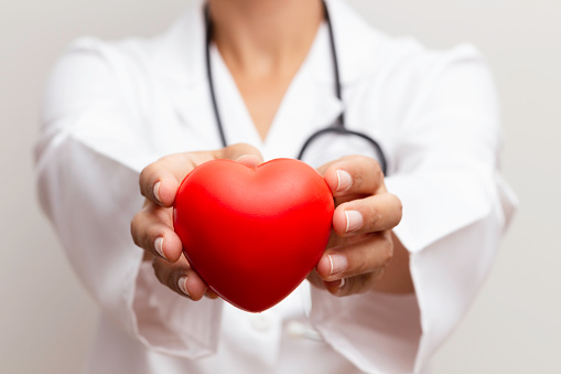 Doctor holding red heart in hand representing organ donation.