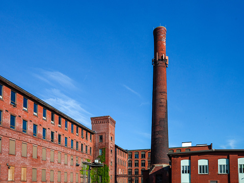 Abandoned multi-story brick factory building with broken glass windows.