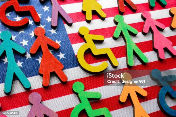 Us Flag And Multicolored Figures With The Symbol Of A Disability Person Stock Photo - Download Image Now