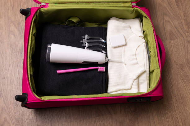 Dental teeth care set in suitcase, travel concept. Water oral teeth irrigator with nozzle pack, toothbrush, floss in luggage on wooden floor. Home dental care device. Horizontal plane Dental teeth care set , mobile devices for health care during traveling, trip. Preparation to journey deep pick stock pictures, royalty-free photos & images