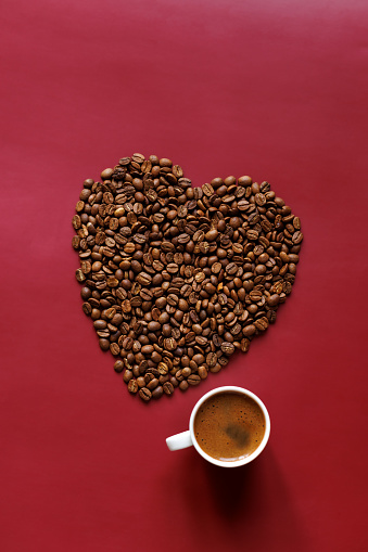 Istanbul, Turkey-January 8, 2023:  Heart shape made with roasted coffee beans on a red background, and Turkish coffee with plenty of foam in a white cup. Valentine's Day concept. Shot with Canon EOS R5.